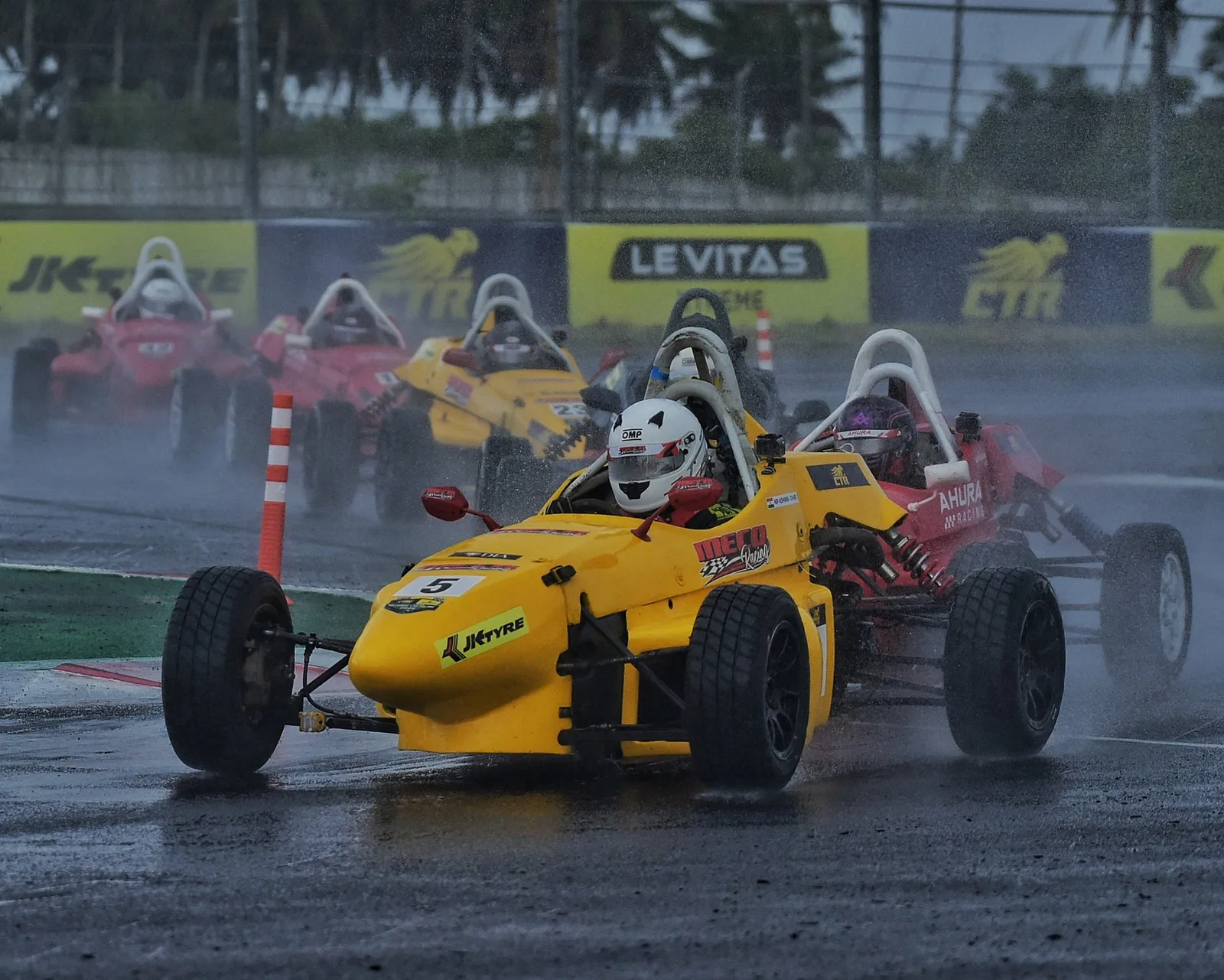 A yellow single-seater on a wet track